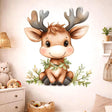 A watercolor illustration of a cute baby reindeer sitting and smiling on a light grey background. The reindeer has large brown eyes, small antlers, and a wreath of green leaves around its neck. Small leafy sprigs are arranged at its feet.