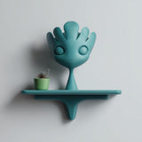 3D printed playful fantasy character wall shelf with rounded cute creature design and integrated shelf, mounted on a clean light interior wall.