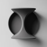 3D printed wall mounted shelf with a sculptural hourglass center and two circular recessed trays, minimalist geometric design, visible print texture on a clean wall.