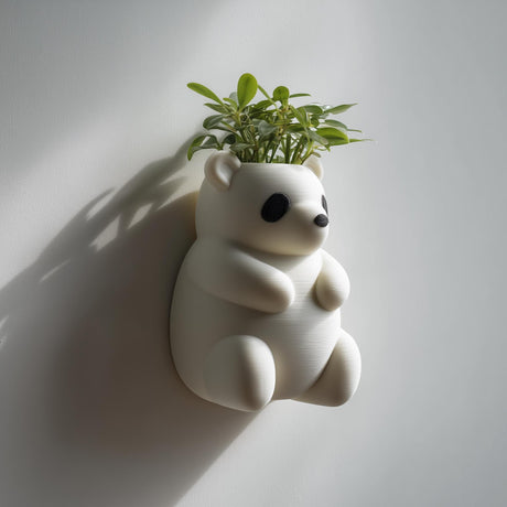 3D printed panda-shaped wall planter pot in matte cream PLA, mounted on a neutral wall and holding a small green houseplant.