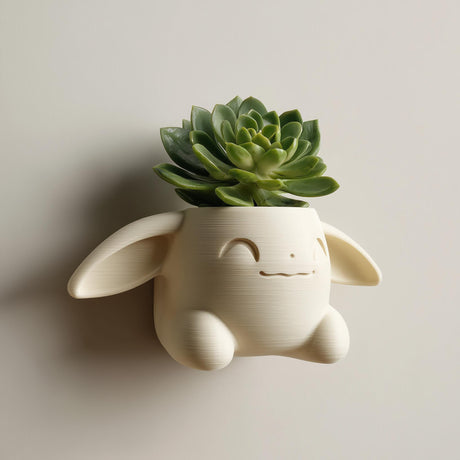 3D printed kawaii bunny wall planter in matte cream PLA mounted on a neutral wall, holding a small green succulent plant.