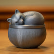 3D printed sleeping woodland animal memorial urn with removable lid in matte PLA displayed on a wooden shelf in warm natural lighting.