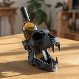 3D printed gothic skull wine bottle holder in matte black PLA holding a standard wine bottle on a wooden table in a cozy interior.
