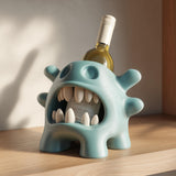 3D printed blue monster wine bottle holder with large teeth holding a wine bottle on a wooden shelf in warm natural lighting.