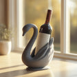 3D printed swan wine bottle holder in matte PLA holding a standard wine bottle near a sunny window.