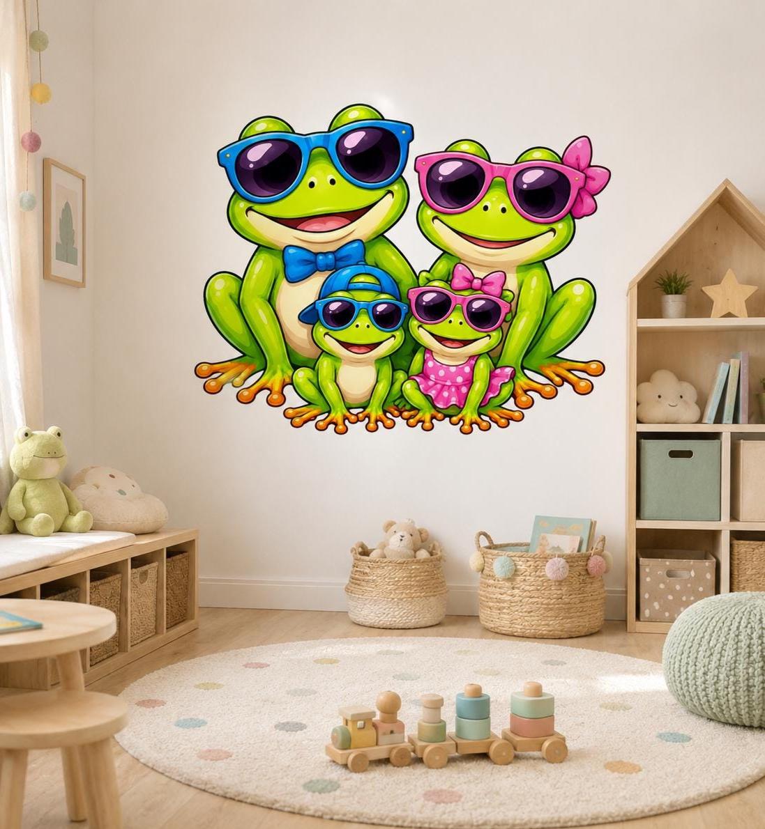 Cute frog family wall vinyl decal with two big frogs and two little frogs wearing sunglasses, with bowties, a cap, and a pink polka-dot dress in a bright cartoon style.