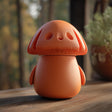 3D printed mushroom memorial urn with character-inspired design and removable lid displayed on a rustic wooden surface in warm lighting.