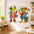 Two bright green cartoon frogs dressed as chefs, wearing oversized white hats and colorful aprons; one holds a whisk and saucepan, while the other holds a carrot and ladle.