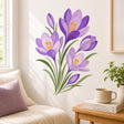 Cluster of purple crocus flowers and buds with golden-orange stamens and long green leaves arranged on a clean white background.