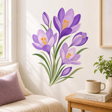 Cluster of purple crocus flowers and buds with golden-orange stamens and long green leaves arranged on a clean white background.