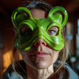 A close-up image of a person wearing a 3D printed, stylized goblincore half-mask. The mask features organic curves with large rounded ear accents, flowing lines around the wide eye openings, and covers the upper face like a whimsical woodland sprite.