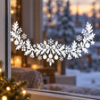 White Christmas window decal with an arched evergreen garland, central bow, hanging ornaments, gifts, bells and snowflakes.