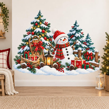 Snowman in a red hat and striped scarf beside a Christmas tree, snowy evergreens, gifts, a sled, lantern and rustic fence.