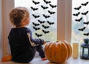 Child sitting by window with Halloween bat decals and a pumpkin, creating a spooky atmosphere.